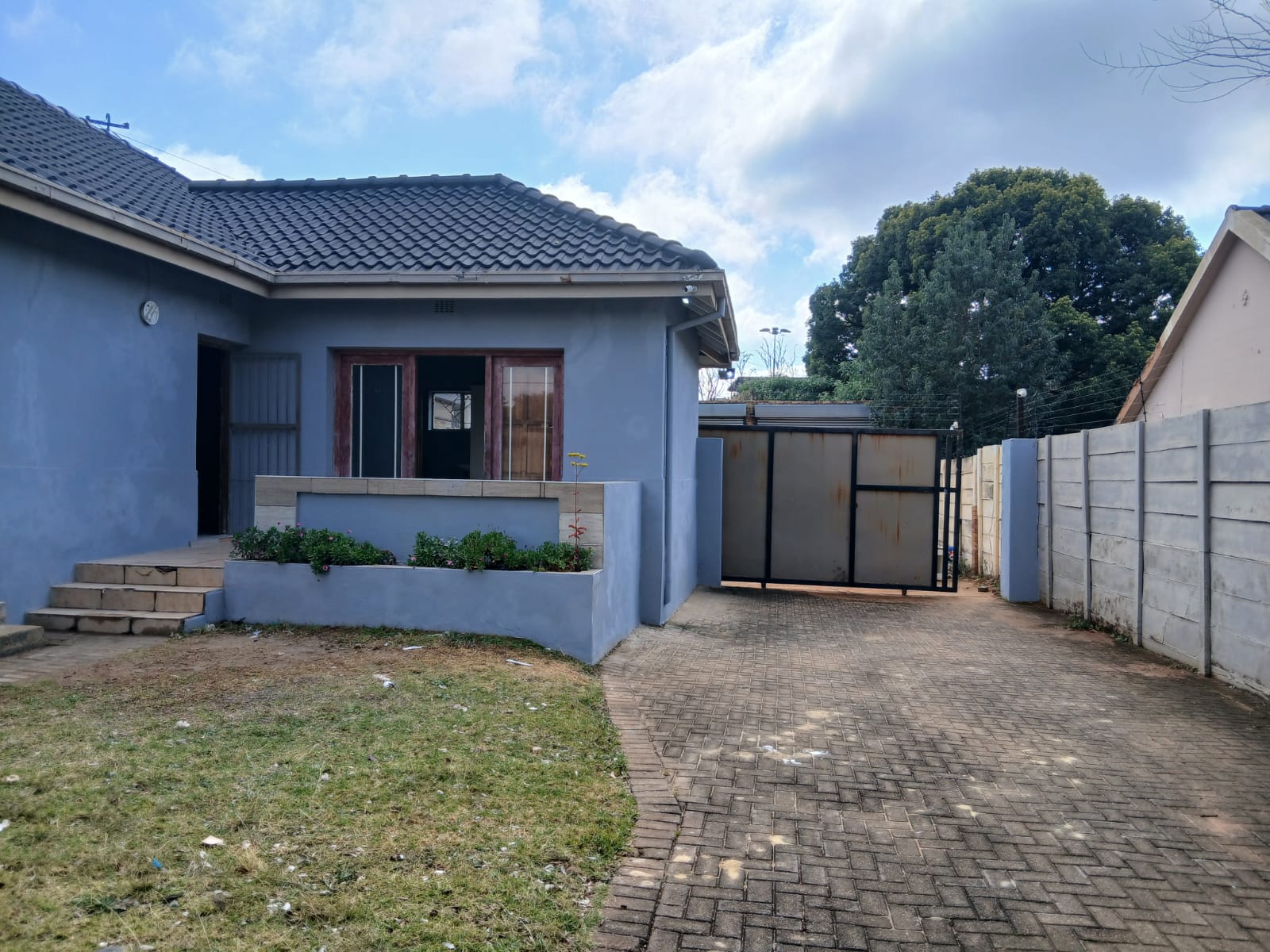Cottage side view with paved driveway and secure gate